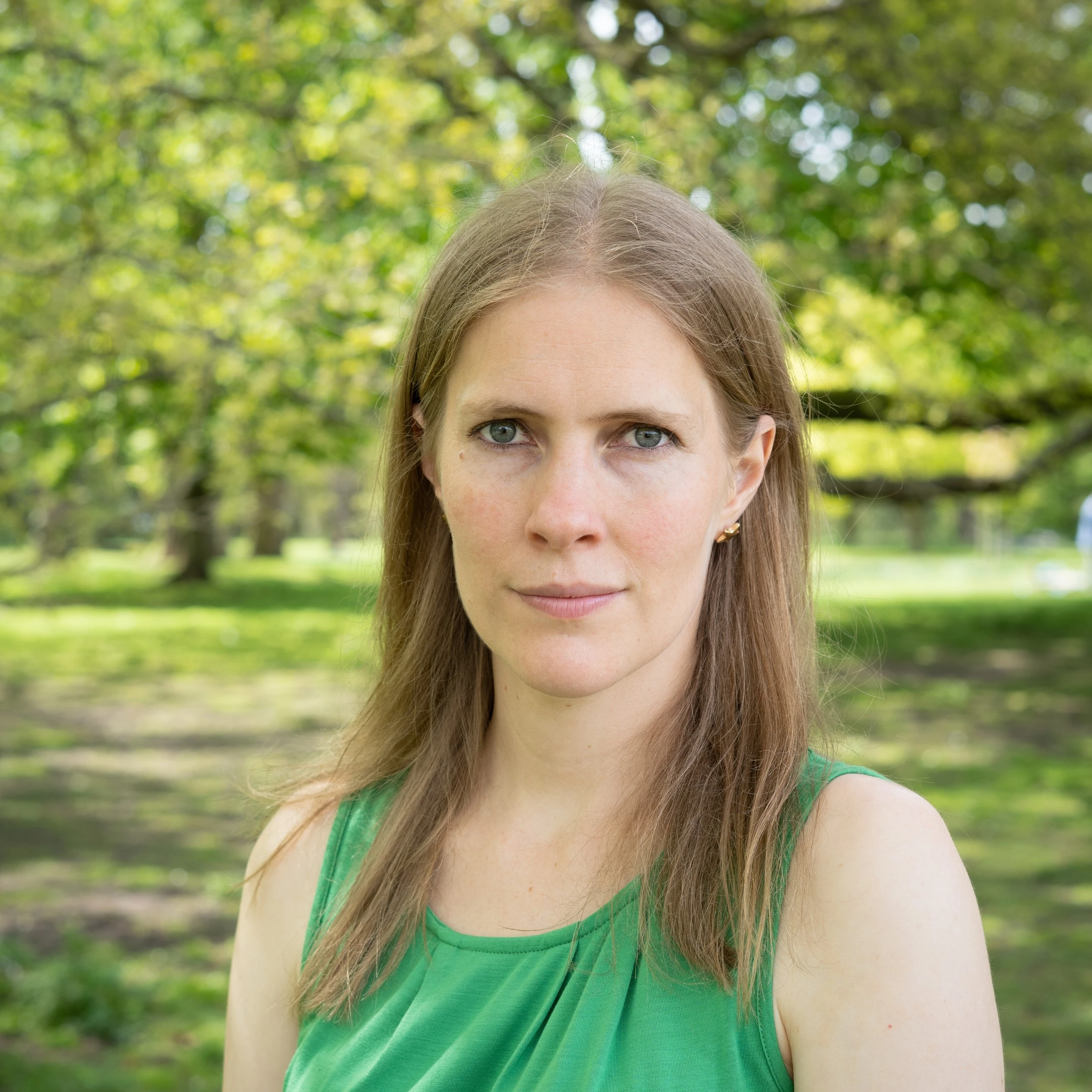 A headshot of Rachel E. Thorn, a white woman with long blonde hair in a green top